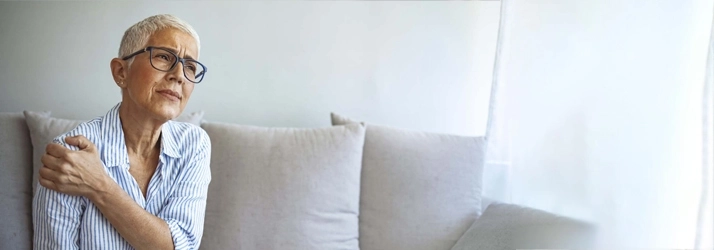 A woman holding her shoulder in pain.