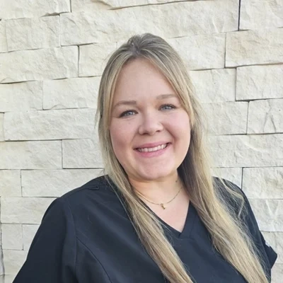 Nurse Practitioner Natalie DeMasters smiling in front of a stone wall.
